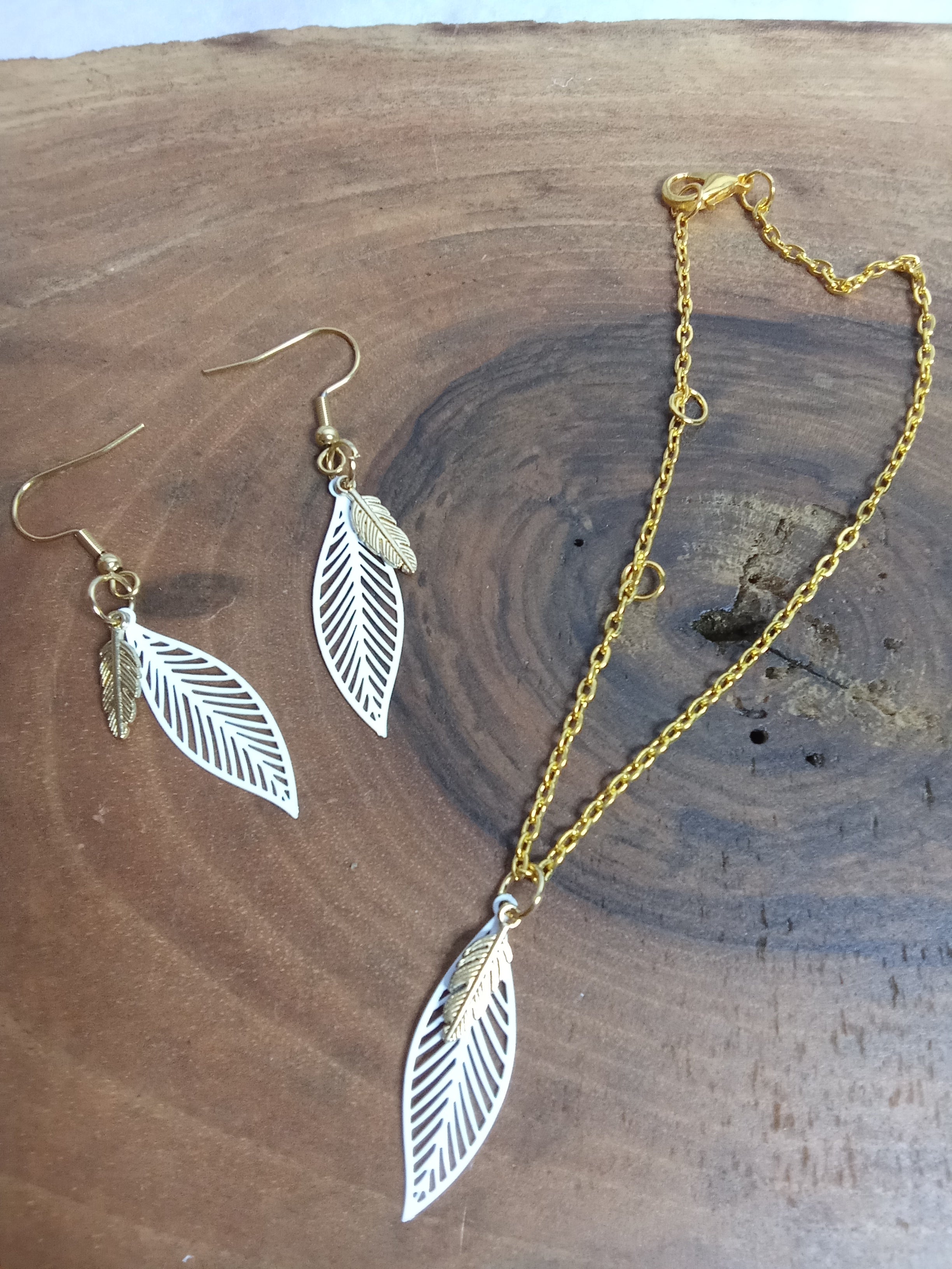 Gros plan boucles d’oreilles et bracelet feuille ajournée sur chaîne dorée